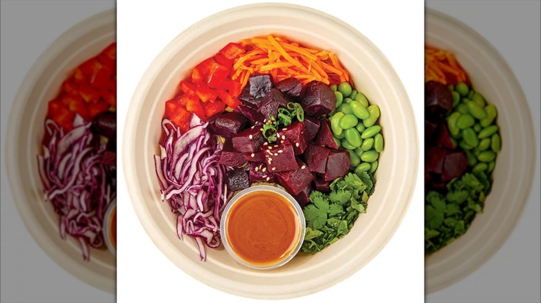 Top view of a salad bowl featuring beats, edamame, carrots, red cabbage, and sauce