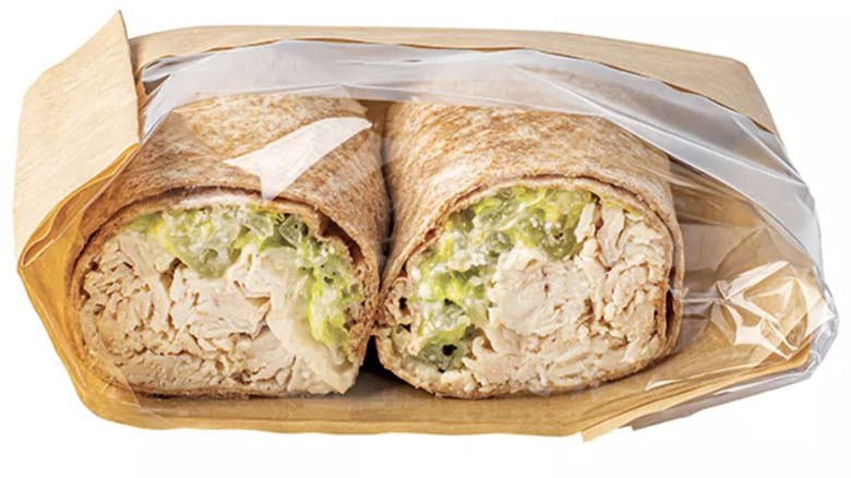 Two halves of a tortilla wrap filled with chicken, salad, and dressing
