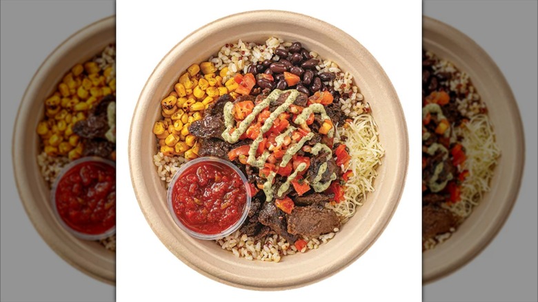 Top view of a bowl featuring corn, rice, meat, salsa, and sauce.