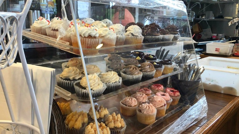 A pastry case full of artisinal cupcakes in different flavors
