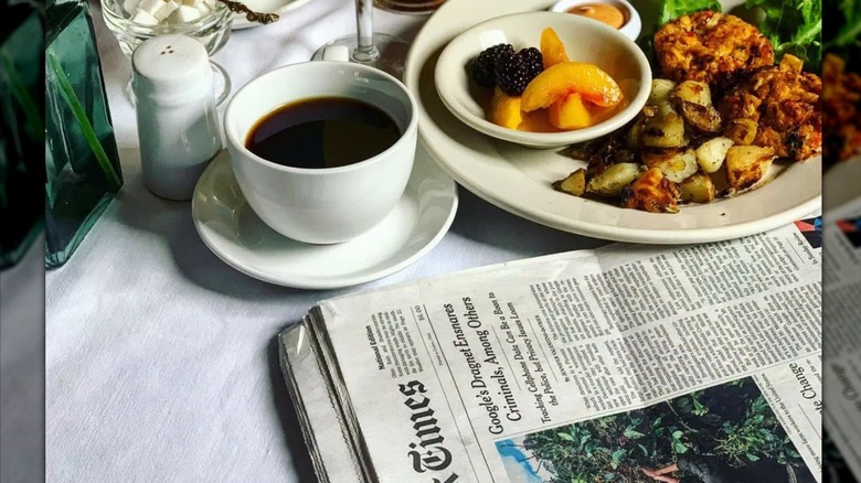 A cup of coffee and country-style breakfast ona  table with a newspaper