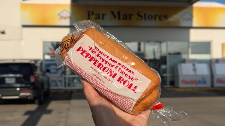 A hand holding a pepperoni roll, a West Virginia staple, outside a gas station