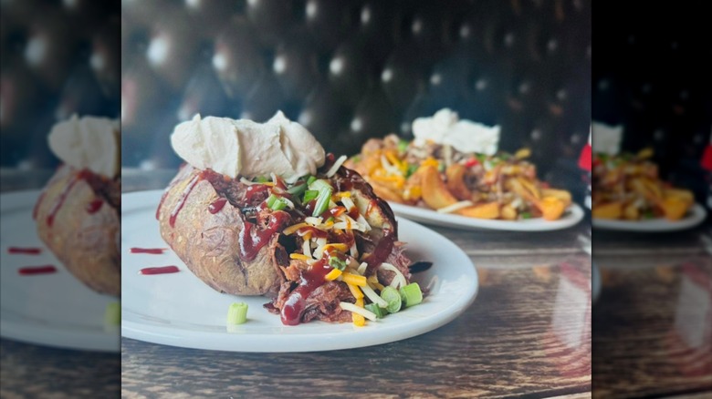 A baked potato with meat and sour cream and another pub dish in the background