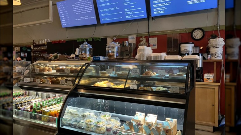 The pastry case and menu on a blue screen over the counter at The Wild Bean
