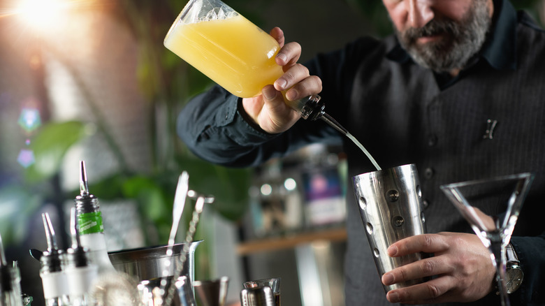Bartender pouring juice into a shaker