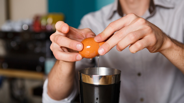 Bartender cracking an egg into a shaker