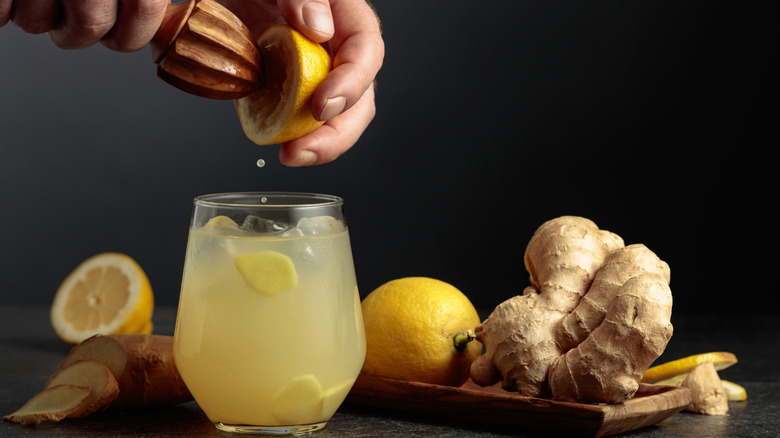 Hands squeezing a lemon into a drink