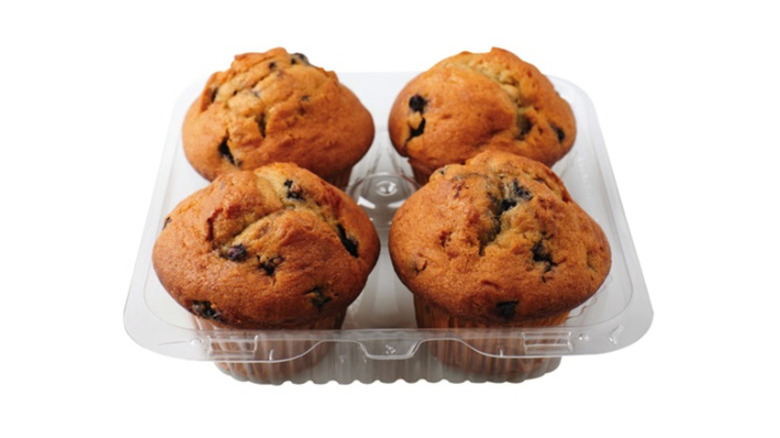 Four pack of blueberry muffins in plastic clamshell container on white background