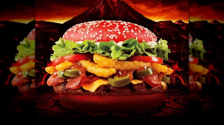 Burger King Angriest Whopper burger with red bun against illustration of volcano in background