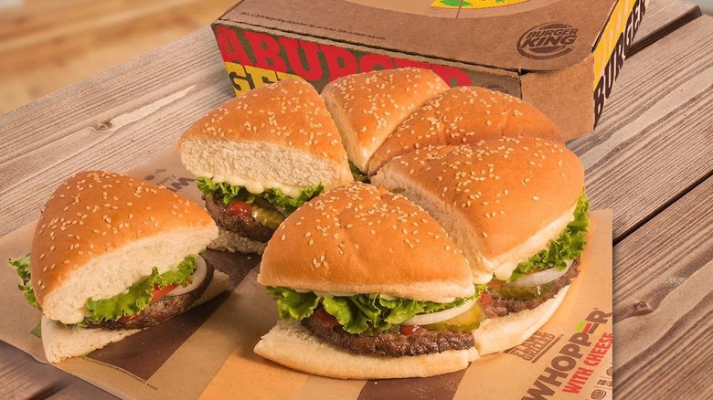 NY Pizza Burger from Burger King cut into wedges sitting on wooden table