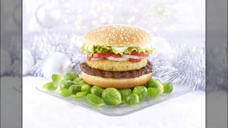 Sprout Surprise Whopper from Burger King sitting on bed of Brussels sprouts with white holiday themed background