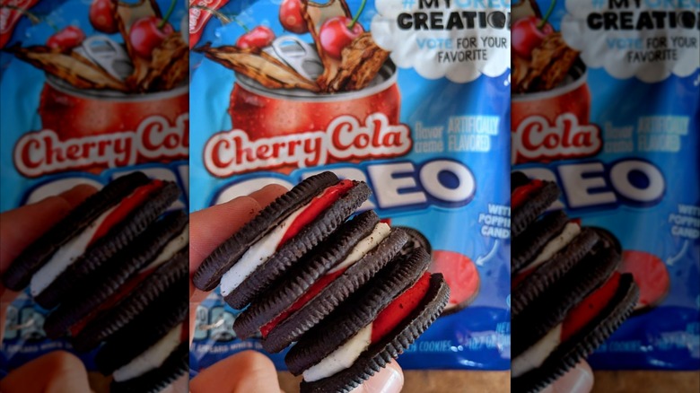 Hand holding stack of Cherry Cola Oreos in front of packaging