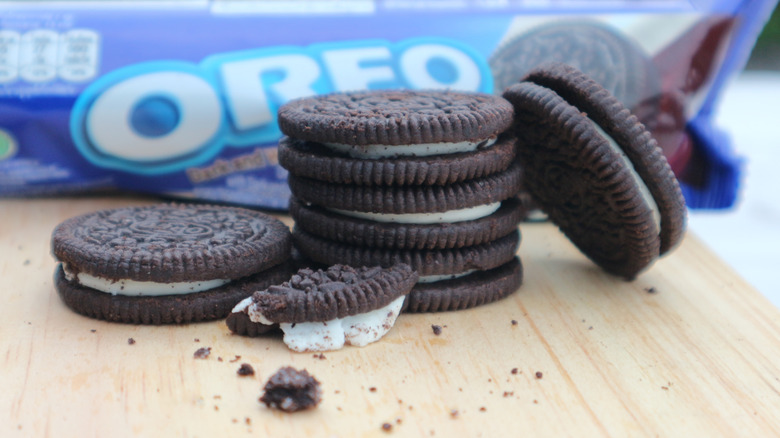 Pile of Oreo cookies on wooden board with packaging in background