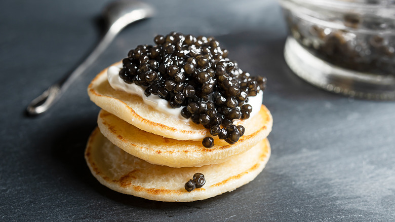 Caviar served on blini with spoon in background.