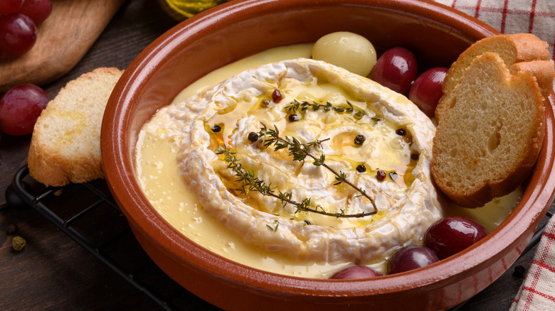 a wheel of brie melting in a crock