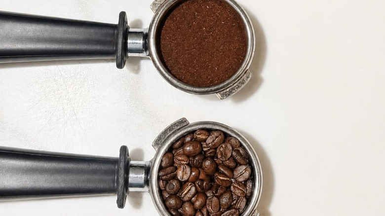 Closeup of coffee beans next to coffee grounds on a white table.