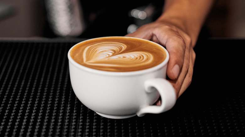 Barista serving a latte in cup.