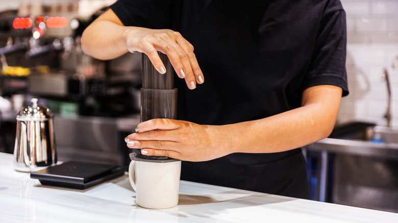 A person using an aeropress coffee device.