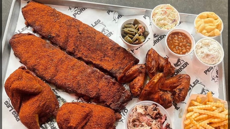 Tray with two racks of ribs, BBQ chicken, pulled pork, fries, and sides