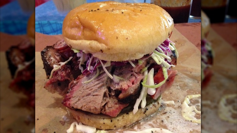 Tipsy Texan sandwich with slaw, sausage, and beers in the background