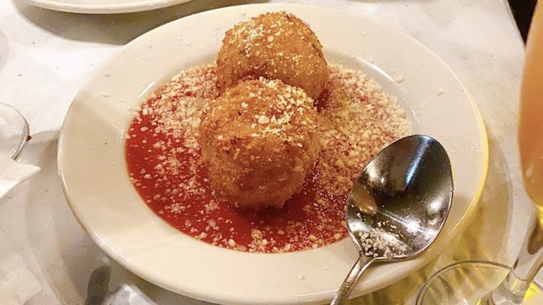 Fried pasta balls on a white plate with marinara sauce from an Italian restaurant in Seattle