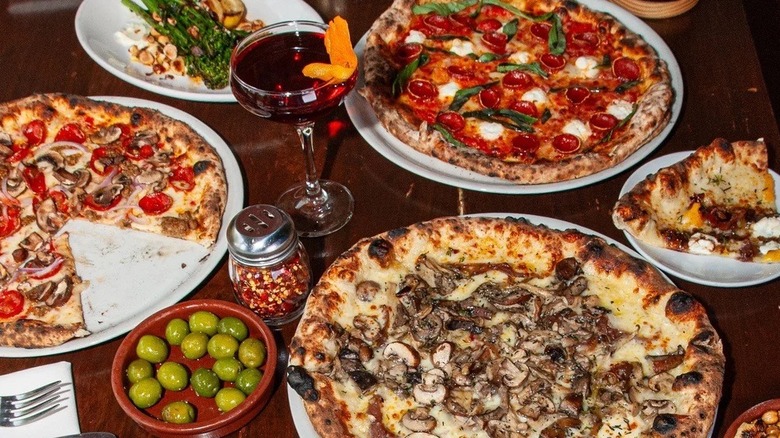 Wooden table with plates of pizza and other Seattle Italian restaurant foods