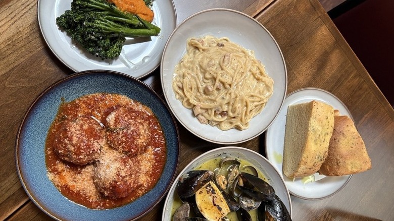 Wooden table with plates of Italian food from Occhi Belli in Seattle