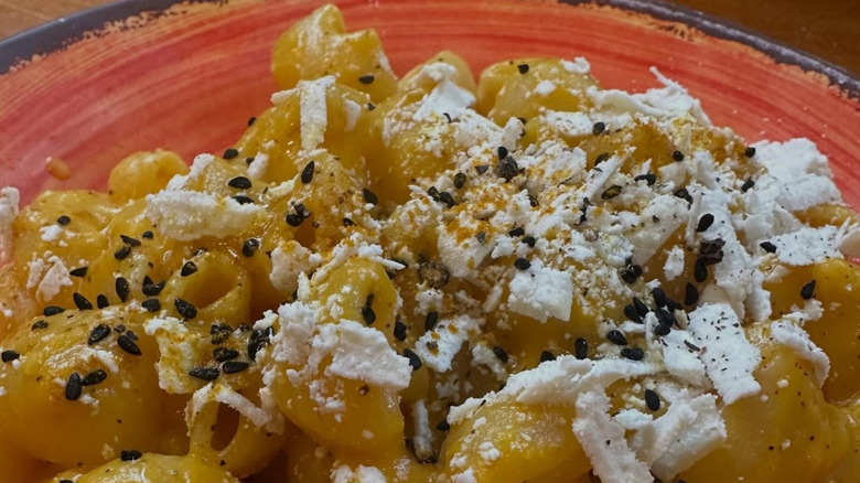 Seattle Italian restaurant plate of butternut pasta in a red bowl with cheese and sesame on top