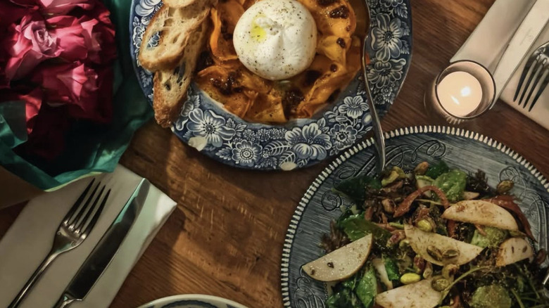 Wooden table with china plates of pasta and salad from San Fermo in Seattle