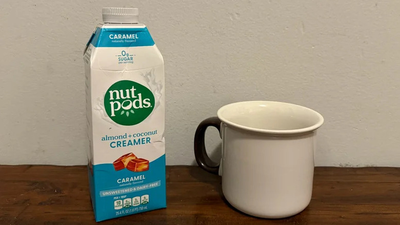 Nut Pods Caramel Unsweetened Creamer on wooden table and a glass