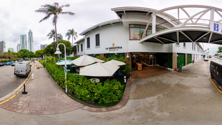 Exterior view of La Industria Bakery with palms and Miami skyline in background