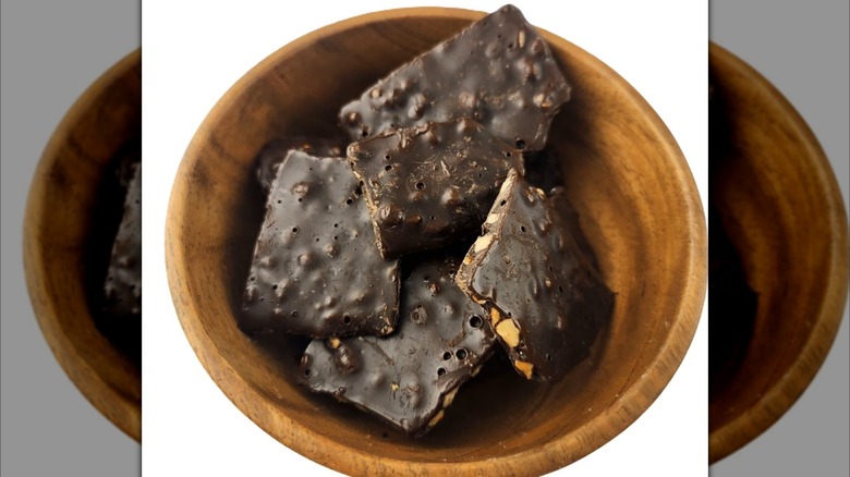 Wooden bowl of dark chocolate thins with almonds and sea salt