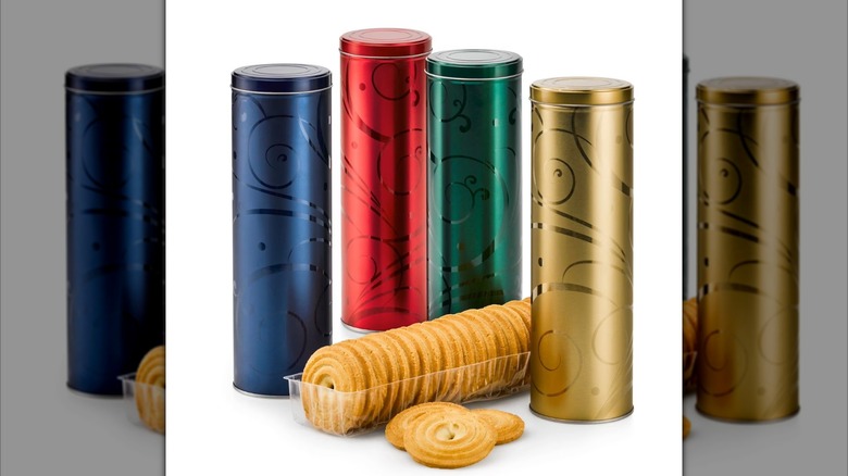 Four tall cookie tins with round shortbread cookies on display