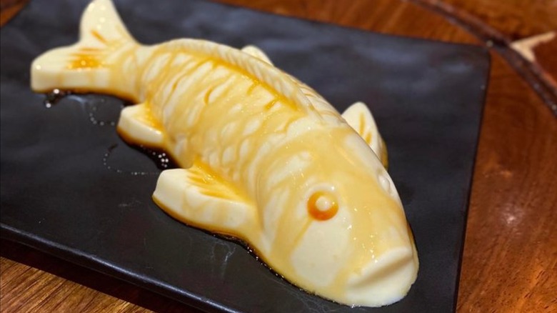 Fish-shaped dessert on a black plate