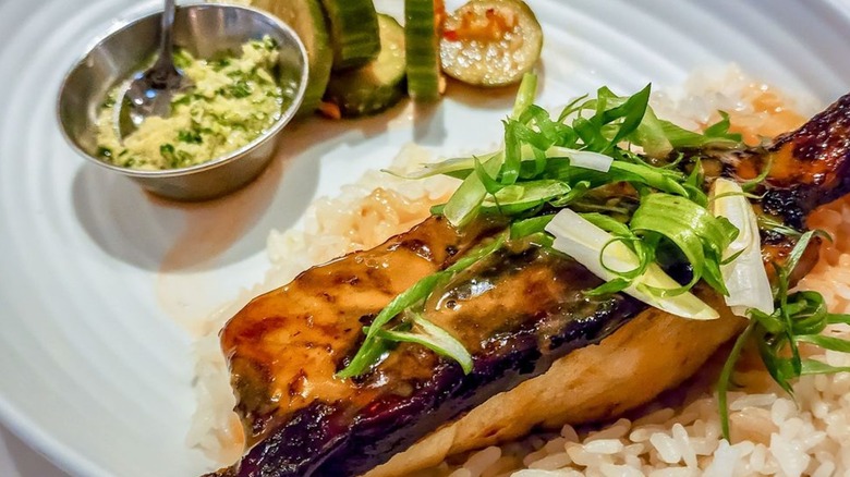 Fish rice with cucumbers on the side on a white plate