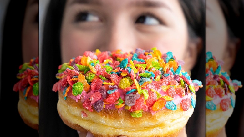 Donut topped with Fruity Pebbles, girl's face behind