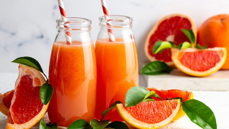 Two bottles of grapefruit juice surrounded by grapefruit pieces