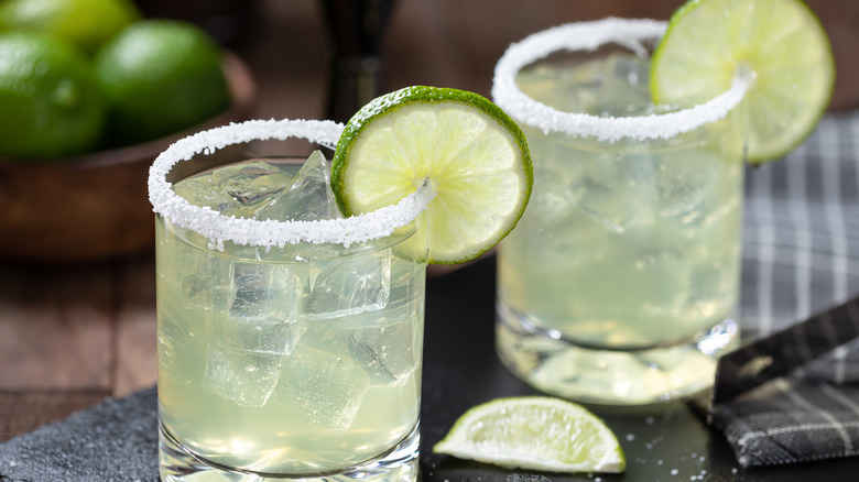 Margaritas in tumblers with lime garnishes