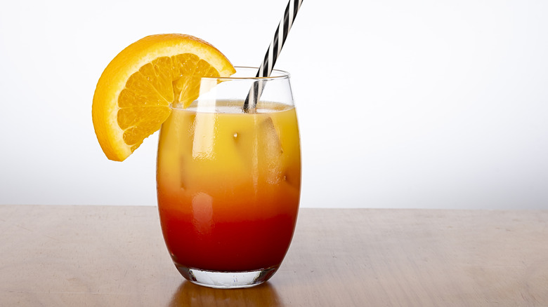 A glass of tequila sunrise with an orange garnish