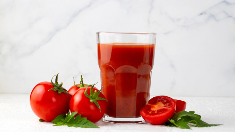 A glass of tomato juice with some whole cherry tomatoes