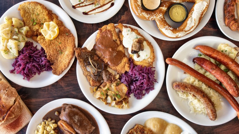 Assortment of plates with German dishes including brats, sausages, schnitzel, and pretezls