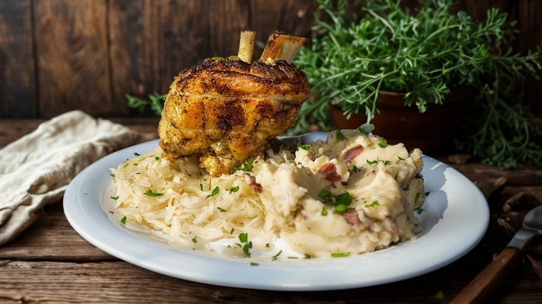 Pork shank with mashed potatoes and sauerkraut on woonden table