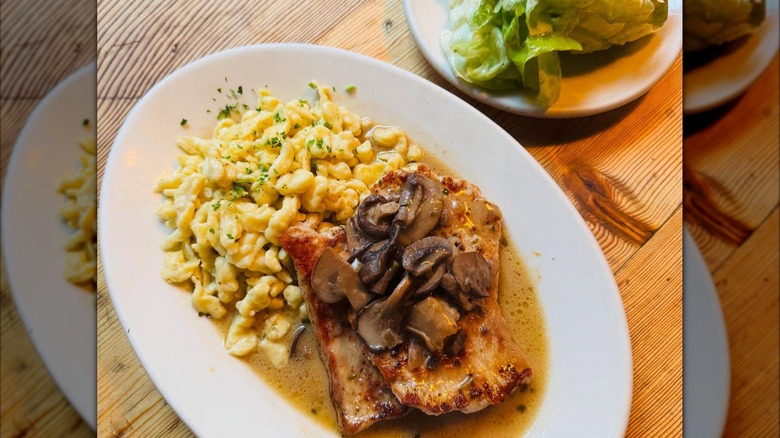 Schnitzel with mushrooms and spaetzle with plate of cabbage