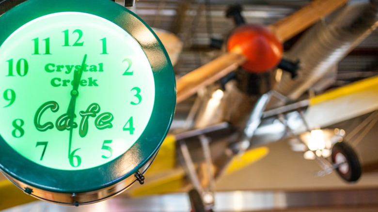A green neon clock with an antique airplane in the background