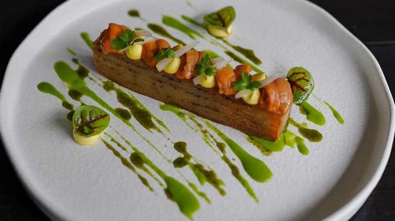 Plated potato and truffle mille-feuille with pickled ramps and egg yolk