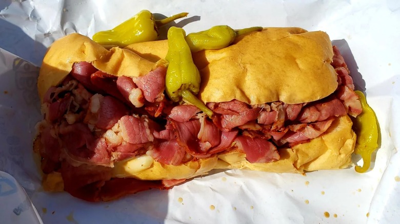 Pastrami sub on paper with whole pepperoncinis