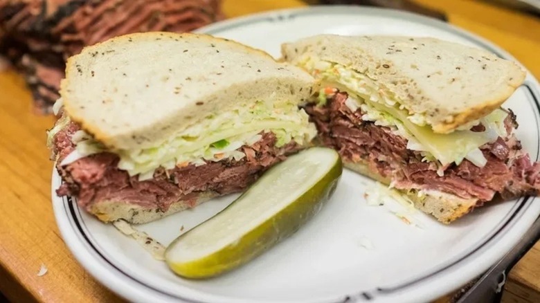 Pastrami sandwich on rye cut in half with half a pickle