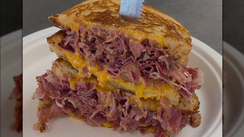 Grilled pastrami sandwich halves stacked on plate