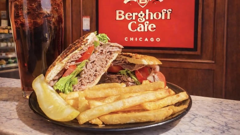 Carved sandwich with fries, pickle, and soda
