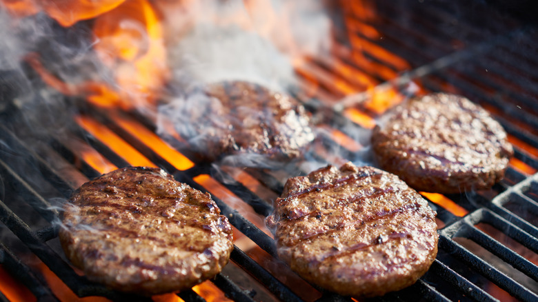 Cooking burgers on a grill with flames